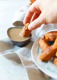 a person dipping sauce on some fried food