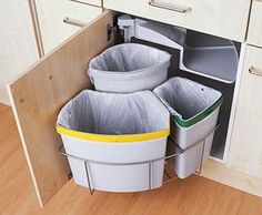 three trash cans in the corner of a kitchen cabinet