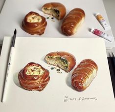 some croissants are sitting on a white paper next to markers and pens