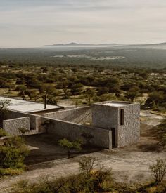 an aerial view of a house in the middle of nowhere with mountains in the background