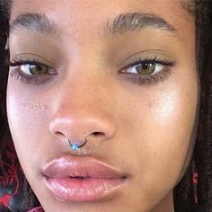 a close up of a person with a nose ring and piercing on her nose looking at the camera