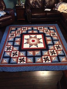 a living room with leather couches and a quilt on the floor