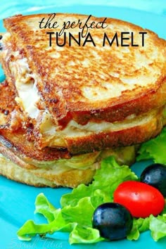 a grilled cheese sandwich with lettuce and black olives on a blue plate