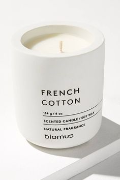 a white candle sitting on top of a table next to a piece of paper that says french cotton