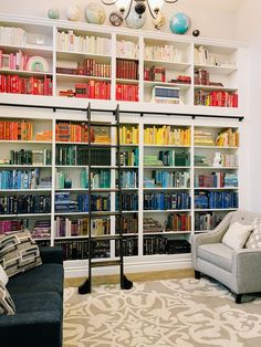 a living room filled with lots of books and furniture next to a white book shelf