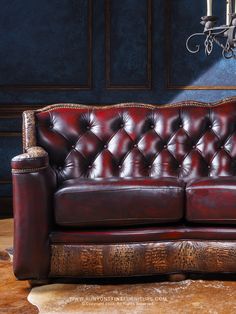 a red leather couch sitting in front of a chandelier