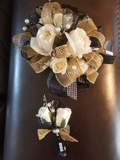 two white flowers are sitting on top of a black leather chair with gold ribbons and bows