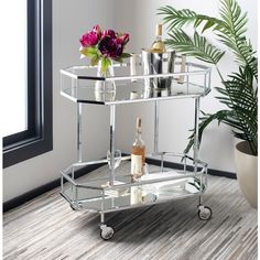 a mirrored bar cart with bottles and glasses on the bottom shelf next to a potted plant