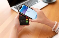 a person using a calculator while sitting at a table in front of a laptop