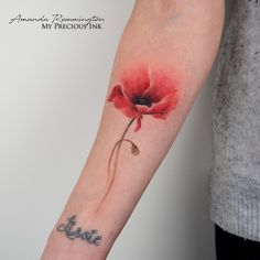 a red flower tattoo on the left arm and wrist, with an arrow in the middle