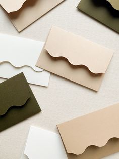 several different colored cards with wavy shapes on the top and bottom one is white, green, beige, and black