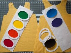 two aprons made out of paper with different colored paint colors on them and one has a pair of scissors next to it