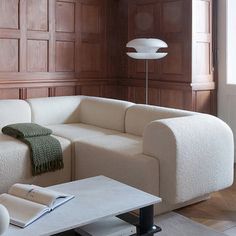 a white couch sitting next to a table in a room with wooden paneled walls