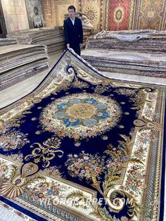 a man standing next to a large rug on the floor in an ornate room with many different colors and patterns