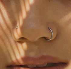 a woman's nose with a silver nose ring on her left side, and the other half of her face visible