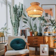 a living room filled with lots of plants next to a wooden table and chair on top of a hard wood floor