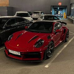 a red sports car is parked in a parking lot next to other cars and trucks