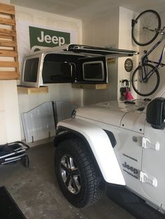 a jeep with a bike mounted to it's roof rack in a garage area