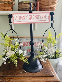 a sign that says bunny crossing sitting on top of a wooden table next to flowers