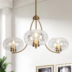 three clear glass globes hang from an antique brass chandelier in a living room