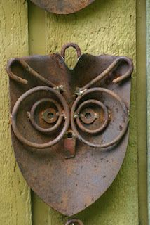 an owl head is mounted to the side of a green door with two bells on it