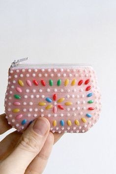 a hand holding a pink purse with colorful beads on it