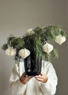 a woman holding a plant with white ornaments on it