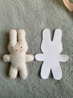 two paper cut out animals sitting next to each other on a bed with a ribbon