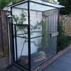 a small greenhouse in the middle of a yard with plants growing out of it's sides