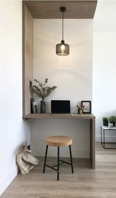 a room with a desk, stool and lamp on it's side in front of a white wall