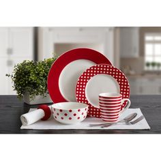 red and white dishes with polka dots on them are sitting next to a potted plant