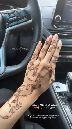 a woman's hand with tattoos on her arm and wrist in a car steering wheel