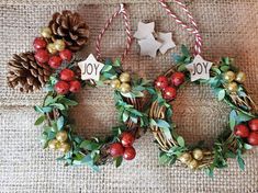 two christmas wreaths with ornaments hanging from them on a burlap tablecloth