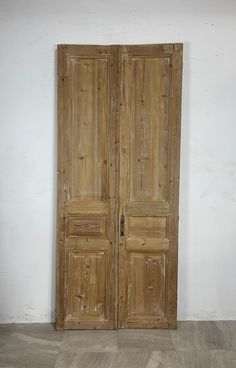 an old pair of wooden doors sitting on top of a hard wood floor next to a white wall