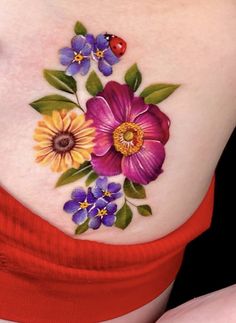 a woman's stomach with colorful flowers and ladybug on the side tattoo