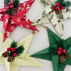 four paper stars with pine cones and holly on them