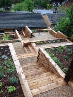 an outdoor garden area with wooden benches and raised planters in the center, surrounded by greenery