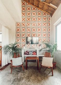 two chairs and a table in front of a wall with an orange pattern on it