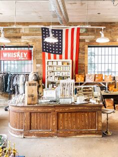 an american flag hangs in the window of a clothing store with clothes and other items on display