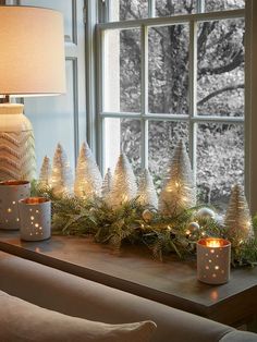 a window sill decorated with candles and christmas trees