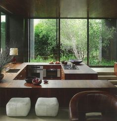 a kitchen with an island counter and stools in front of large windows overlooking trees