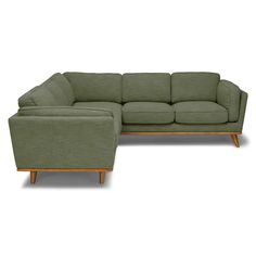 a green sectional couch sitting on top of a white floor next to a wooden frame