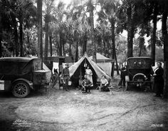 an old black and white photo of people in front of tents with cars parked next to them