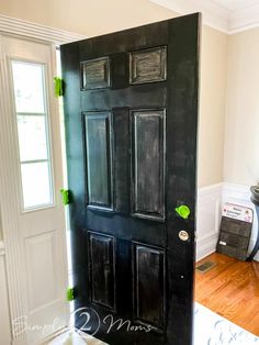 a black front door with green knobs on the side and white trim around it