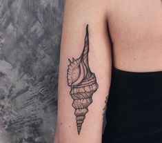 a woman's arm with a black and white sea shell tattoo on her left arm