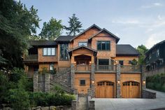 a large wooden house with two garages on the front and second story, surrounded by trees