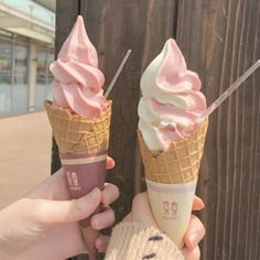 two people holding ice cream cones in their hands