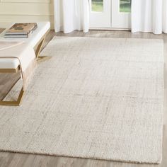 a white rug in front of a window with curtains and a bench on the floor