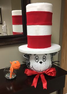 the cat in the hat is next to a fish bowl