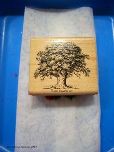 a rubber stamp with a tree on it sitting in a blue container next to a white towel